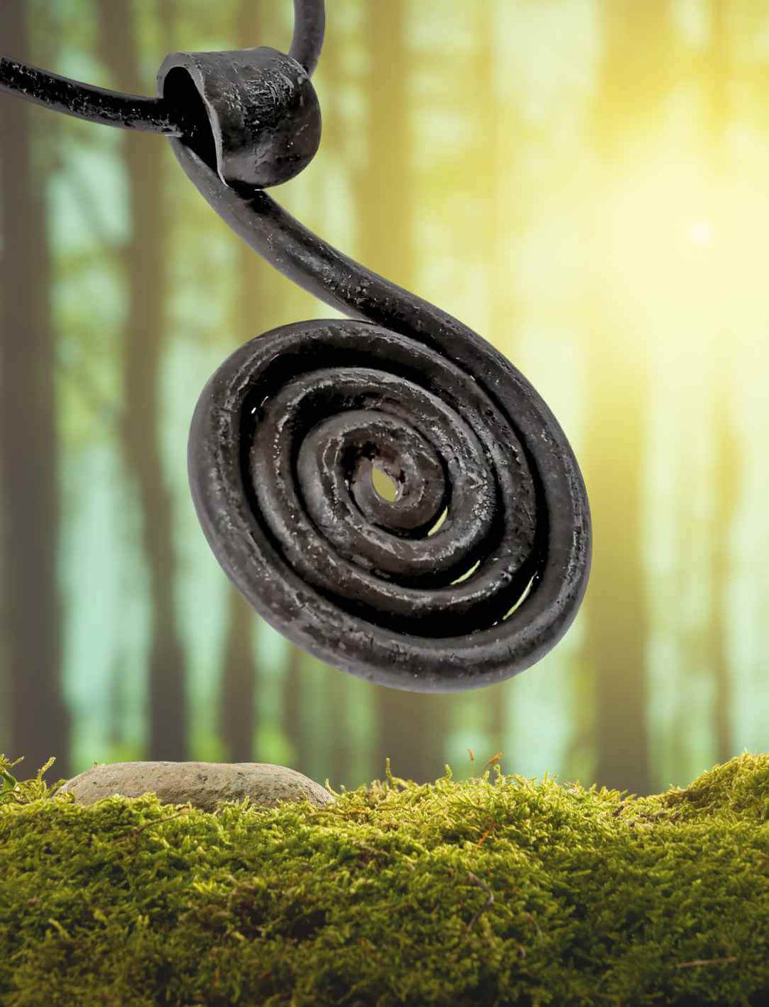 Das geschmiedete Solsnurra â Sonnenzeichen von Midgard Amulett schwebt vor einem nebelverhangenen Wald. Die spiralförmige Sonne symbolisiert Licht, Schutz und die ewige Wiederkehr des Tages.