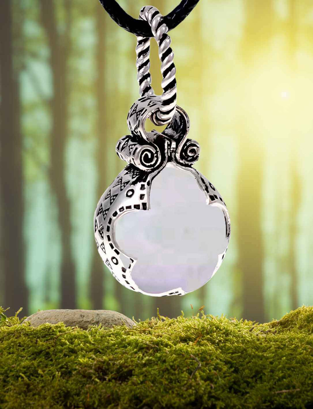 Sphäre des Nordlichts Wikinger-Anhänger aus versilberter Bronze mit Glas, präsentiert mit Lederband auf Wald/Moos Hintergrund.