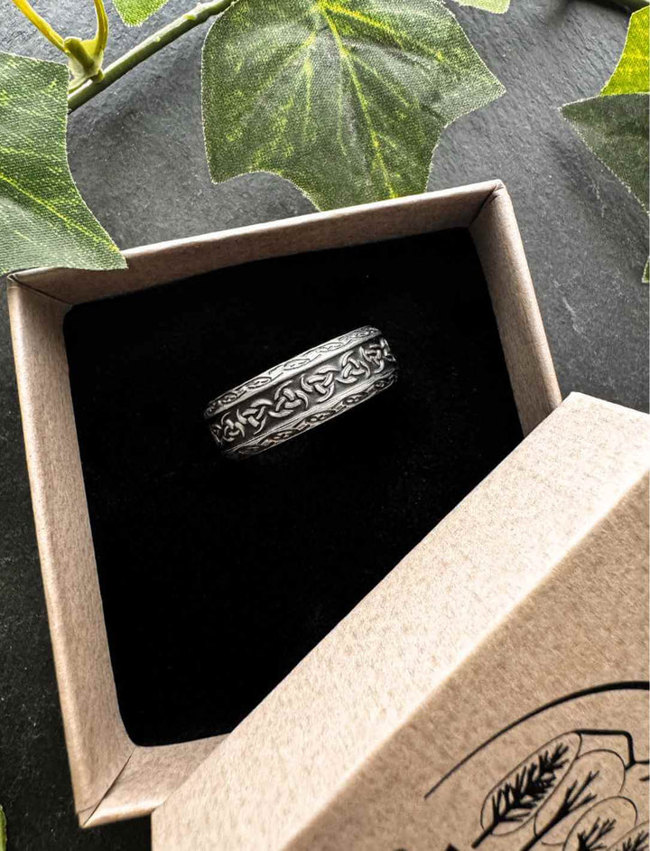 Trícha – Ring der Drei Kräfte aus Edelstahl, stilvoll fotografiert in einer Runental Geschenkverpackung auf Steintisch mit Efeu Deko.