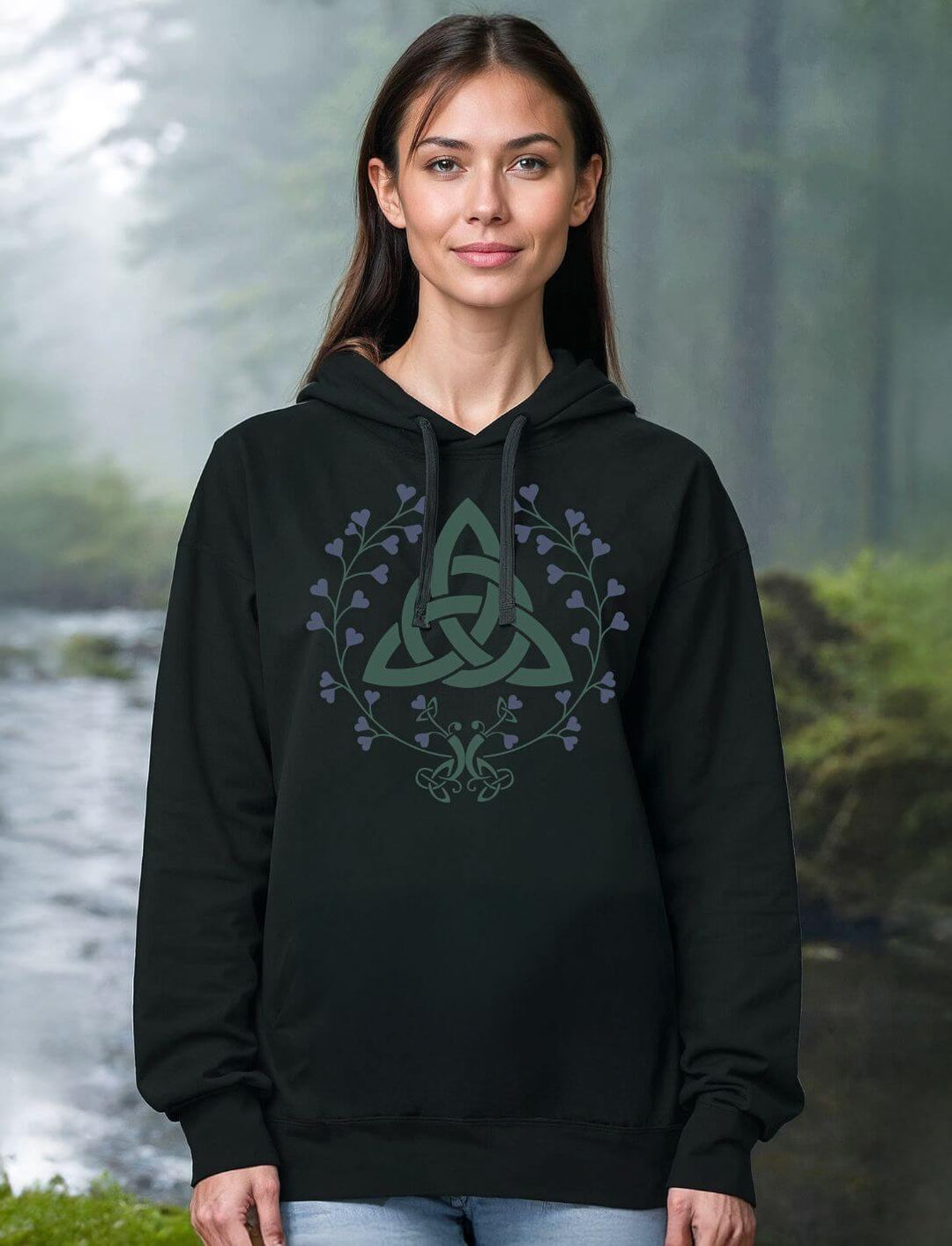 Person trägt den „Triquetra des grünen Bundes“ Hoodie in Schwarz – mit floraler Triquetra und mystischer Waldstimmung im Hintergrund.