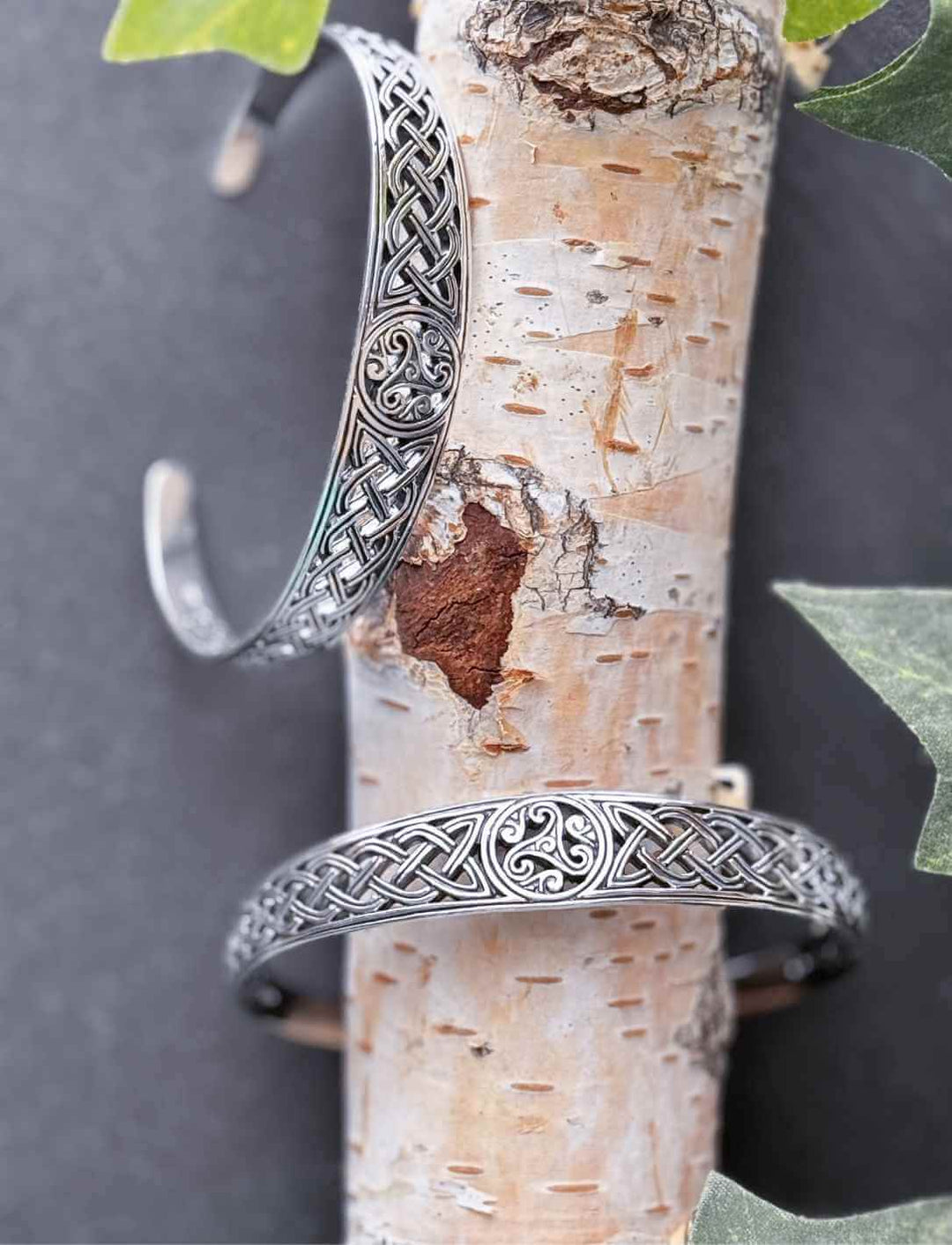 Keltischer Silberarmreif mit Triskele und Knotenmuster auf Birkenrinde dekoriert mit Efeu