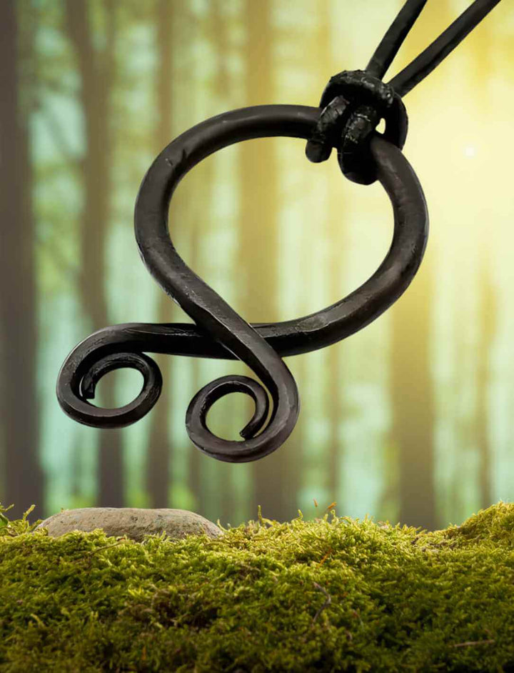 Trollkreuz des Nordens, handgeschmiedet aus Eisen, auf Moos im Wald platziert. Ein Amulett der Wikingerzeit, das vor bösen Geistern und Trollspuk schützt, getragen als Zeichen der Wehrhaftigkeit.