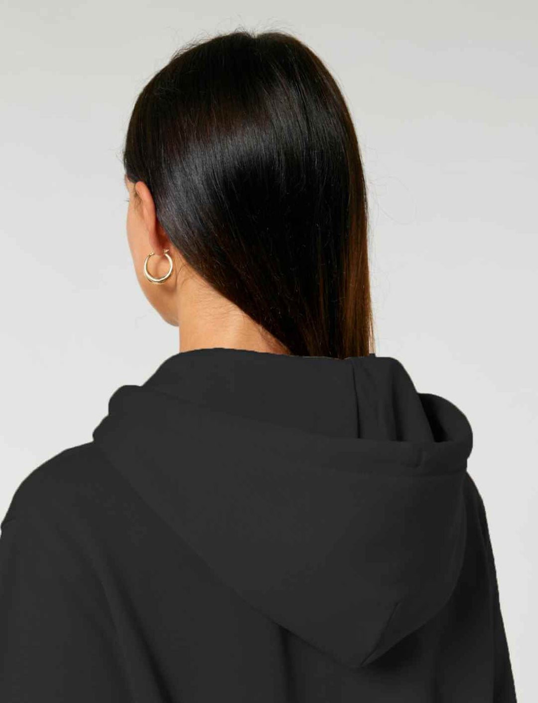 Rückansicht einer Frau mit Kapuze – die Kapuze liegt locker auf dem Rücken und betont die legere Passform.