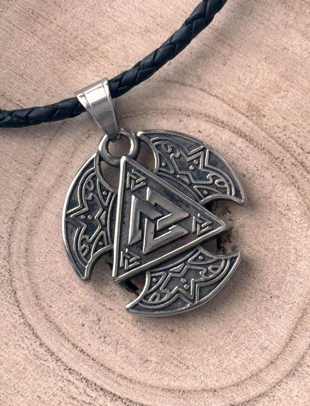 Valknut Schild des Schutzes, mit gedrehter Lederkette, auf hellem Holzhintergrund.