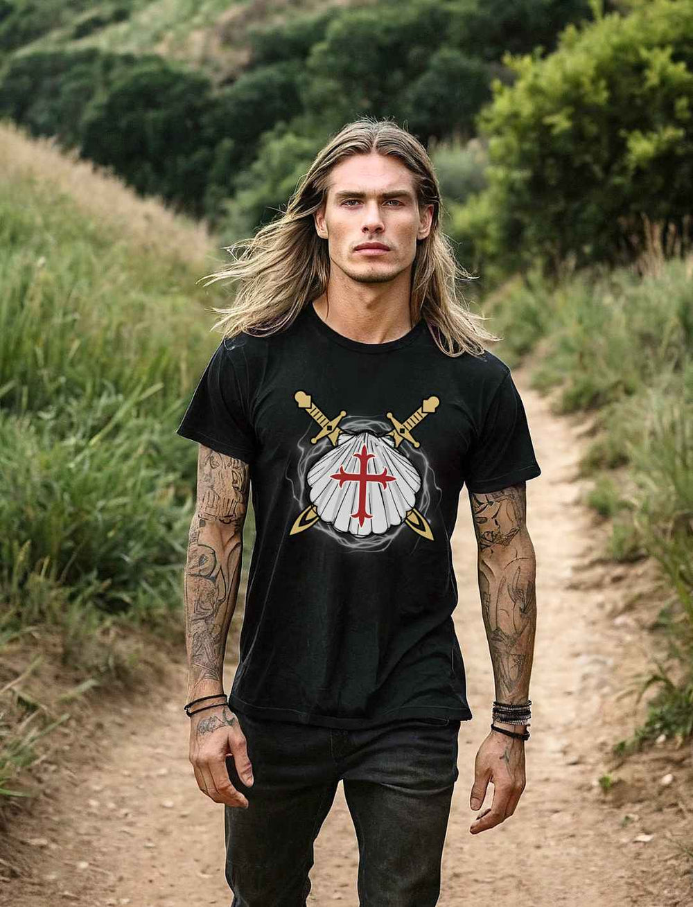 Männliches Model mit langen Haaren und Tattoos trägt das schwarze 'Wächter des Sternenwegs' T-Shirt,  auf einem naturbelassenen Pfad