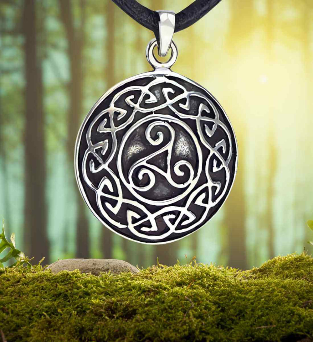 Keltische Dreieinigkeit Anhänger, hervorgehoben gegen einen natürlichen Moos- und Waldhintergrund – Runental.de.