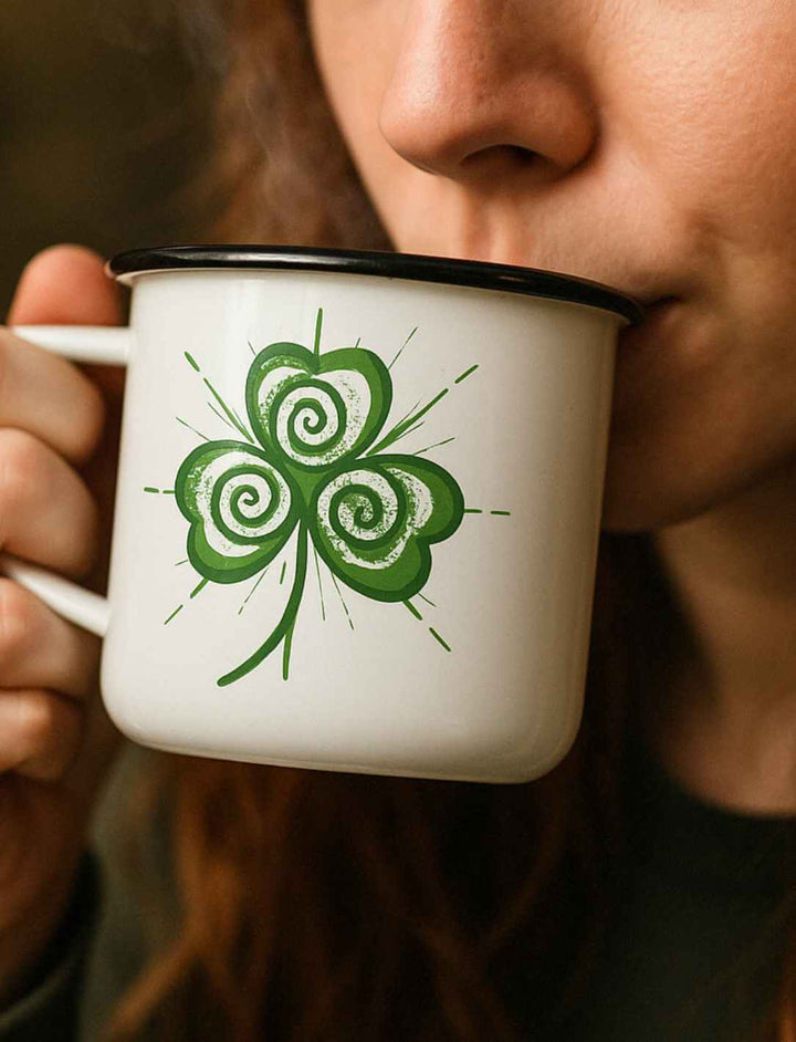 Junge Frau trinkt aus der EMaille Tasse Trifolia Mystica, weiss mit schwarzem Rand.