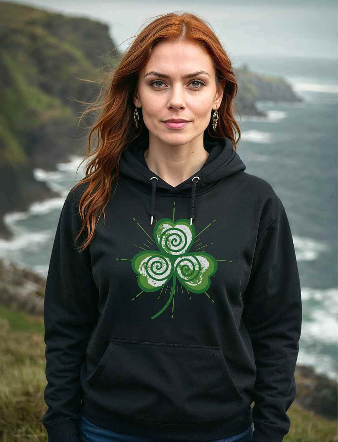 Frau trägt den Trifolia Mystica Hoodie in Schwarz vor dramatischer irischer Küstenlandschaft – stilvoll & mystisch zugleich.