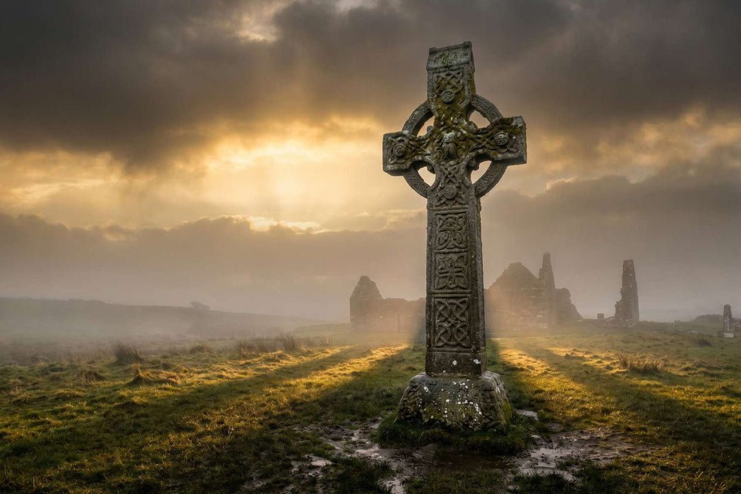 Verwittertes irisches Hochkreuz mit keltischen Flechtbändern im dramatischen Seitenlicht, Irland