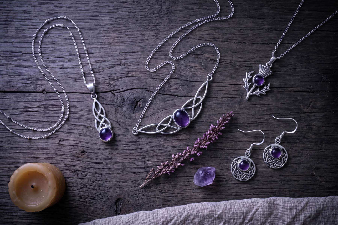 Amethyst-Schmuck von Runental auf dunklem Holz mit Heidekraut, Kerze und Amethyst-Rohsteinen