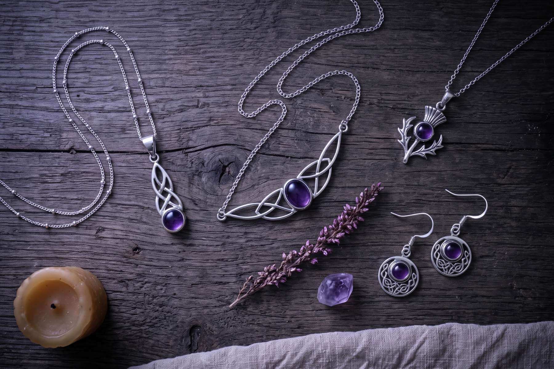 Amethyst-Schmuck von Runental auf dunklem Holz mit Heidekraut, Kerze und Amethyst-Rohsteinen