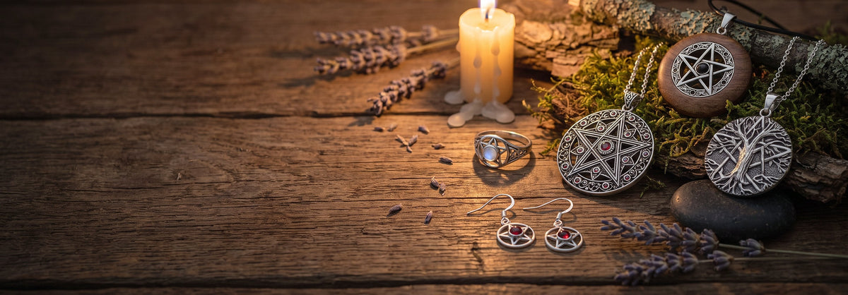 Pentagramm Schmuck aus Silber mit Granat und Mondstein auf altem Holztisch neben brennender Kerze, Lavendel und Moos