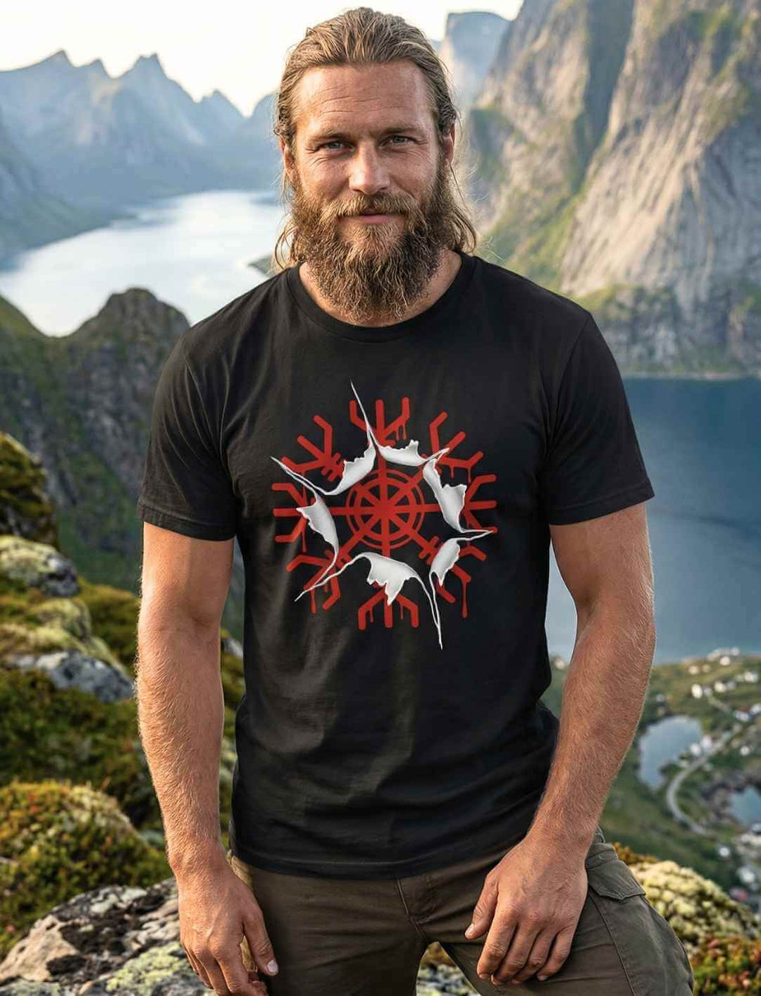 Männliches Model trägt schwarzes aegishjalmur Awakening Shirt mit rotem Helm der Ehrfurcht im Riss-Design vor nordischer Bergkulisse