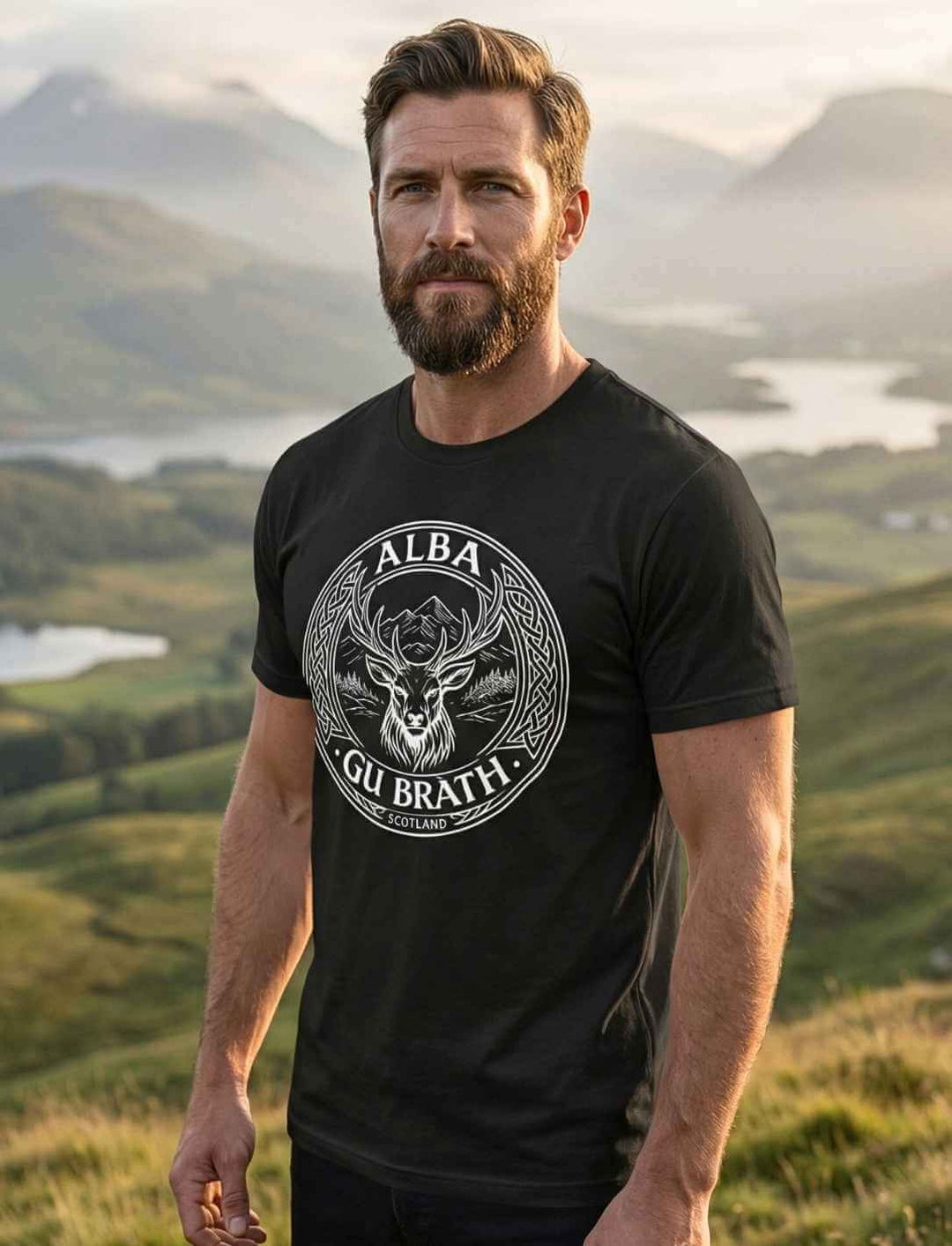 Mann trägt Alba gu bràth Unisex T-Shirt Schwarz mit keltischem Hirsch Emblem in schottischer Highlands Landschaft