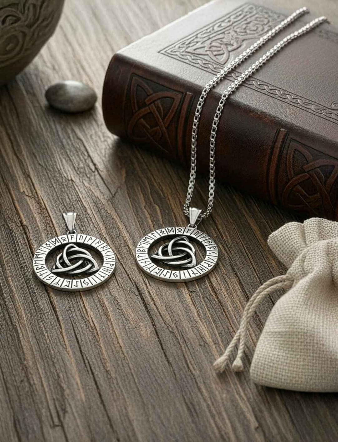 Keltisch-nordisches Edelstahl-Amulett mit Triquetra und Runen, gezeigt mit Kette und Schmuckbeutel – Symbol für Stärke und Einheit