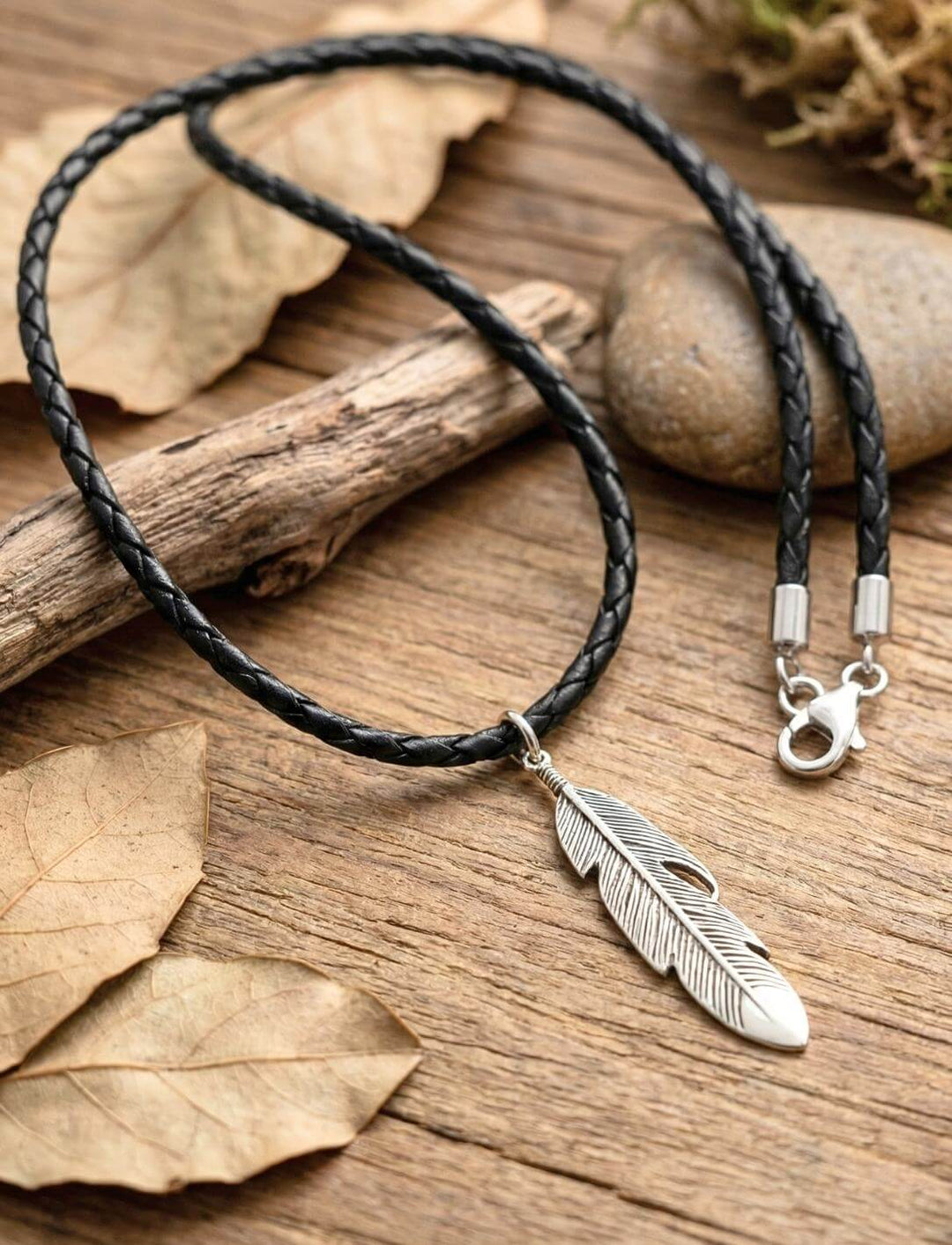 Anam Cara Silberfeder Anhänger an geflochtener Lederkette auf Herbstlaub und Treibholz