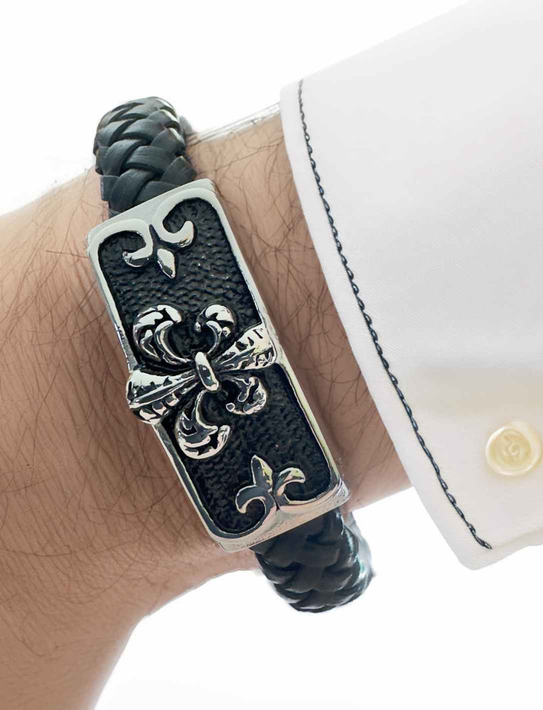 Armband der Noblesse – Geflochtenes Lederarmband mit Edelstahlschließe und Fleur-de-Lis-Motiv, getragen von Männerhand mit weißem Hemd