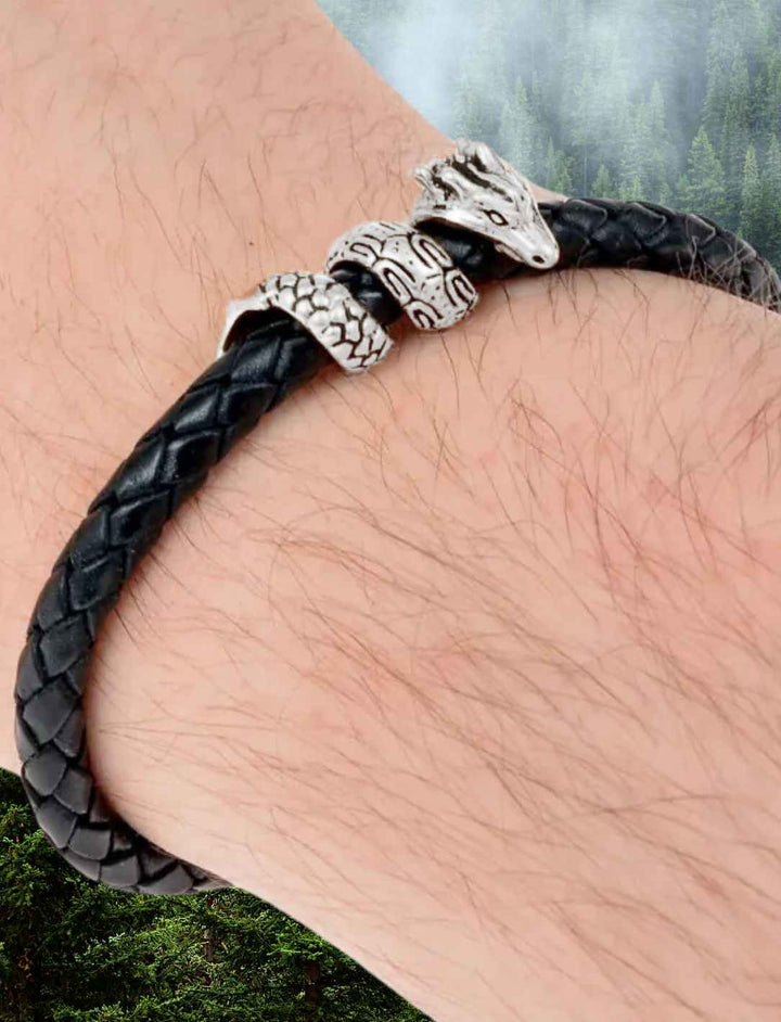 Nahaufnahme eines Männerarms, der das Armband des Drachens mit geflochtenem Leder und versilbertem Drachenkopf trägt.