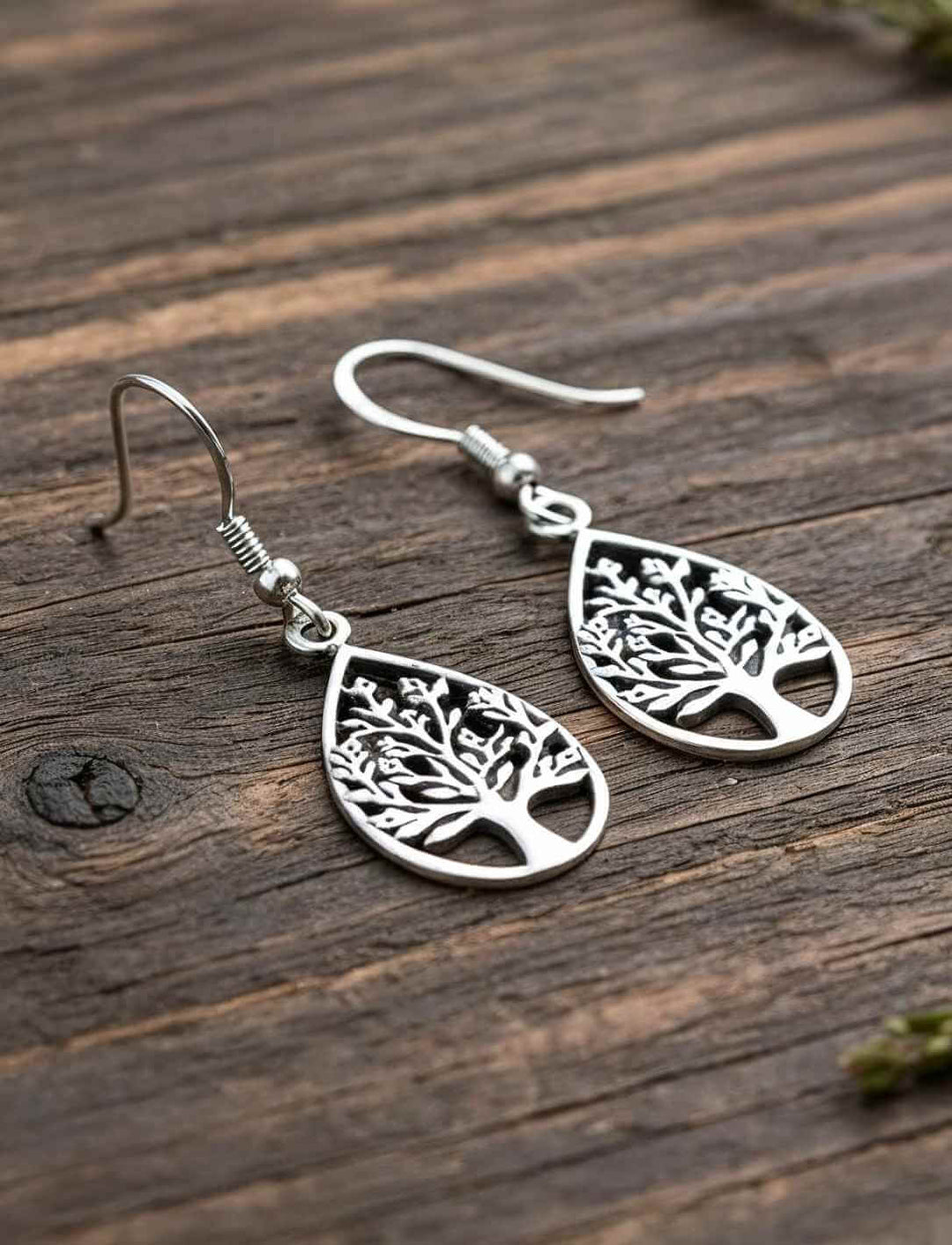 Feine Lebensbaum Silberohrringe in tropfenförmiger Blattform auf naturbelassenem Holz