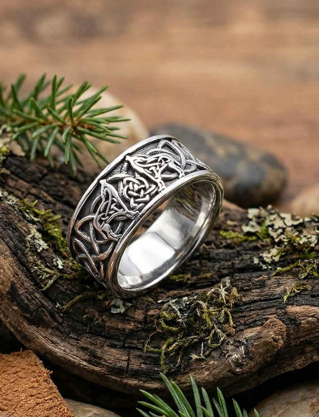Keltischer Silberring mit Wolfs- und Knotenmuster aus Edelstahl liegend auf Holz und Moos in naturverbundener Szene