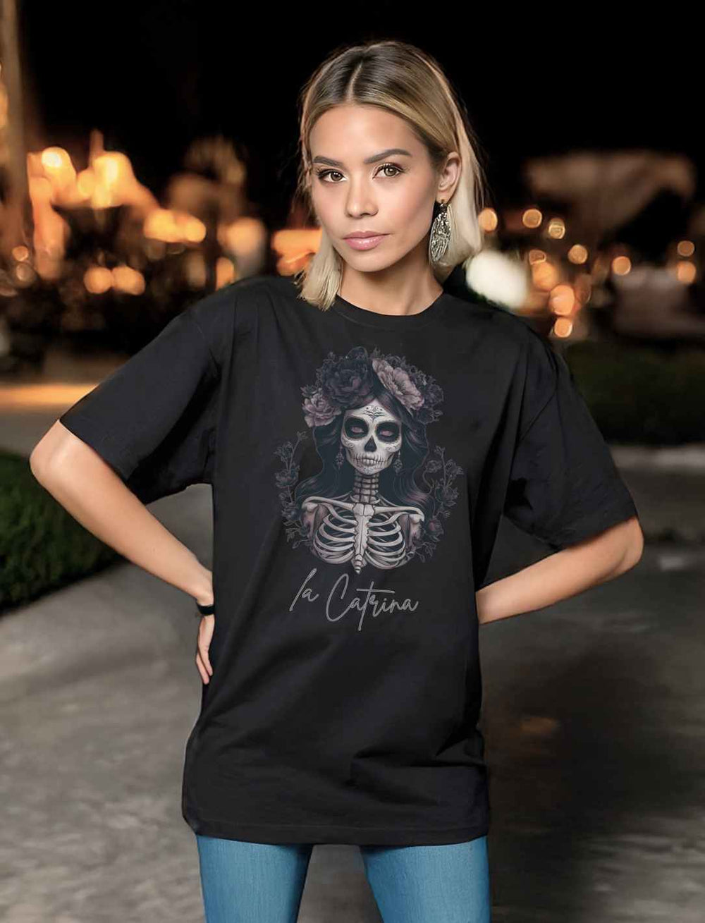 Modell trägt das Catrina Deluxe Unisex Organic Heavy Oversized Shirt in Schwarz, präsentiert bei Nacht mit stimmungsvollem Hintergrund, kombiniert mit blauen Jeans.