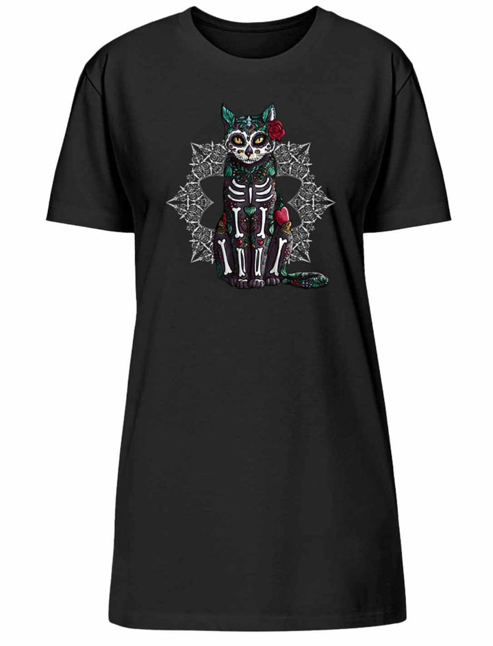 Frau trägt ein „Catrina Felina“ T-Shirt Kleid in Schwarz von Runental.de. Mystisches Design mit Katzenmotiv inspiriert vom Día de los Muertos, im Abendlicht auf einer gepflasterten Straße abgebildet.