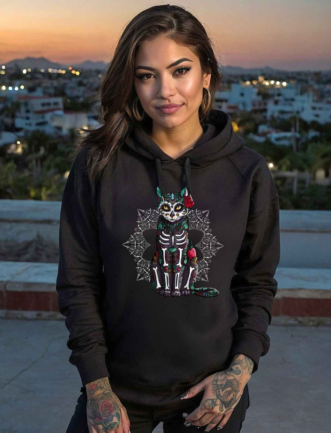 Frau bei Sonnenuntergang trägt Catrina Felina Unisex Hoodie in Schwarz – Mystischer Katzengeist im Día de los Muertos Stil, verziert mit floralen Details, bei Runental.de erhältlich