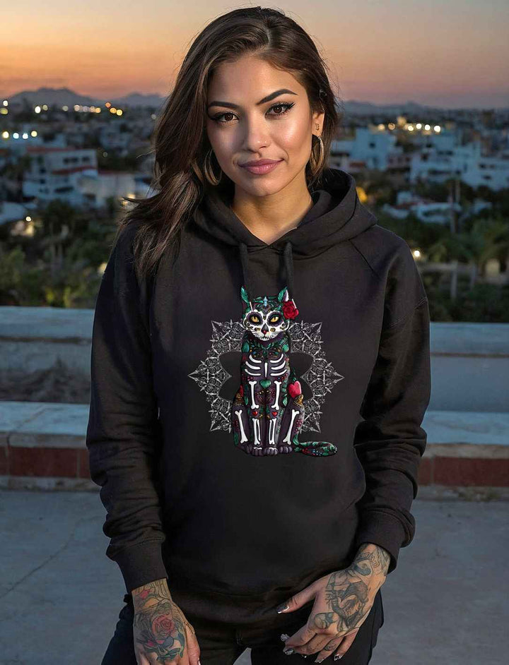 Frau bei Sonnenuntergang trägt Catrina Felina Unisex Hoodie in Schwarz – Mystischer Katzengeist im Día de los Muertos Stil, verziert mit floralen Details, bei Runental.de erhältlich