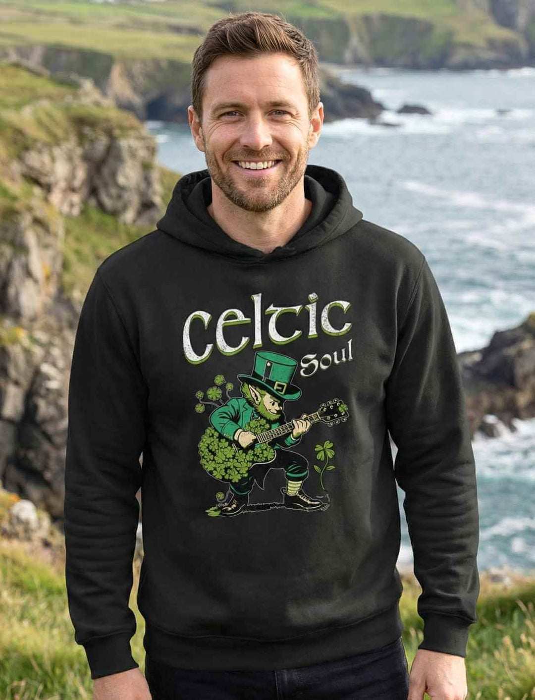 Celtic Soul Organic Hoodie in Schwarz – Herren Kapuzenpullover mit Leprechaun Gitarrenmotiv vor irischer Küstenlandschaft