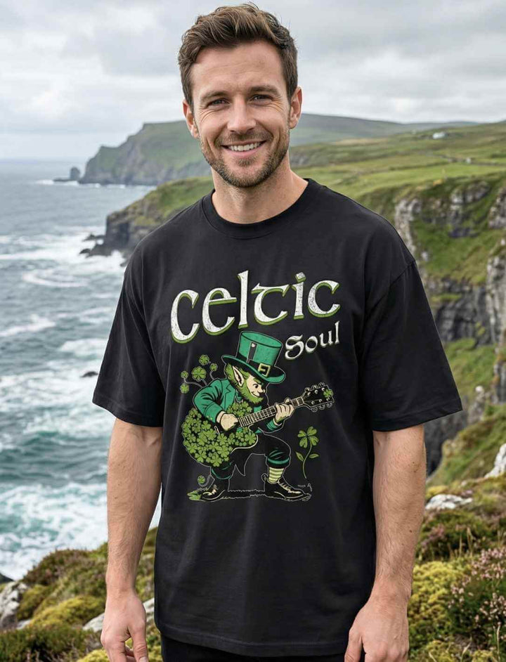 Oversized Herren T-Shirt „Celtic Soul“ mit Leprechaun Motiv vor irischer Küstenlandschaft – lockerer Relaxed Fit, schwarzes Irish Design Shirt