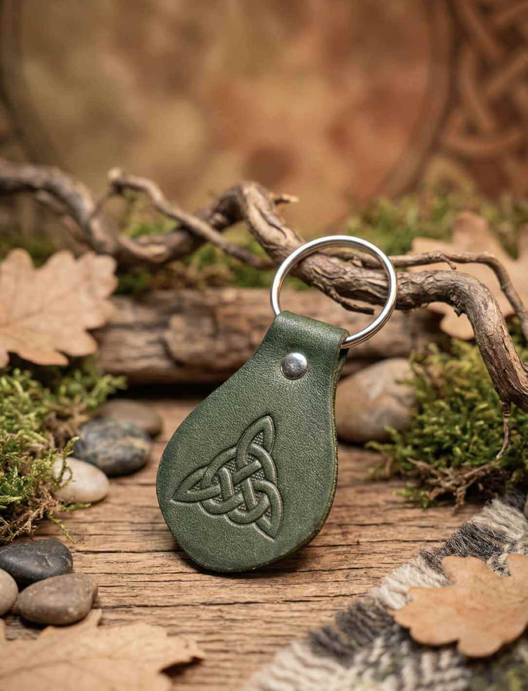 Grüner Leder Schlüsselanhänger mit keltischem Trinity Knot, auf Holz und Moos arrangiert