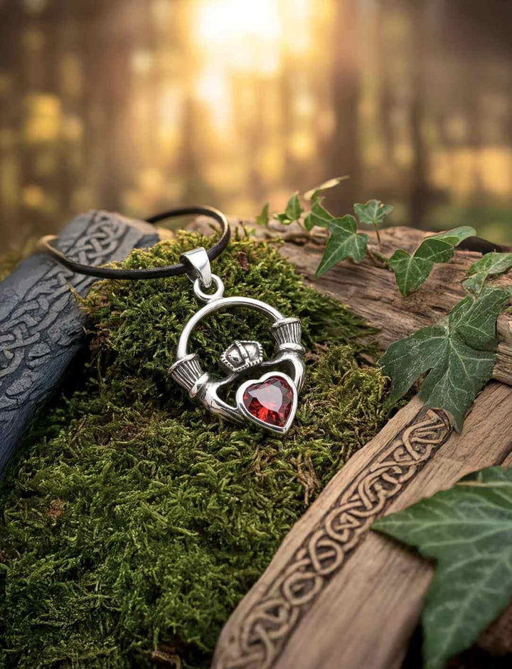 Claddagh Medaillon aus 925 Silber mit rotem Herzstein, arrangiert auf Moos und Holz
