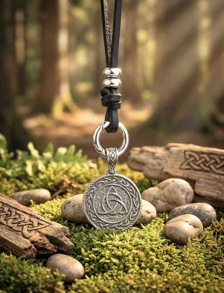 Keltischer Triquetra Anhänger hängend am Band, fotografiert im warmen Waldlicht