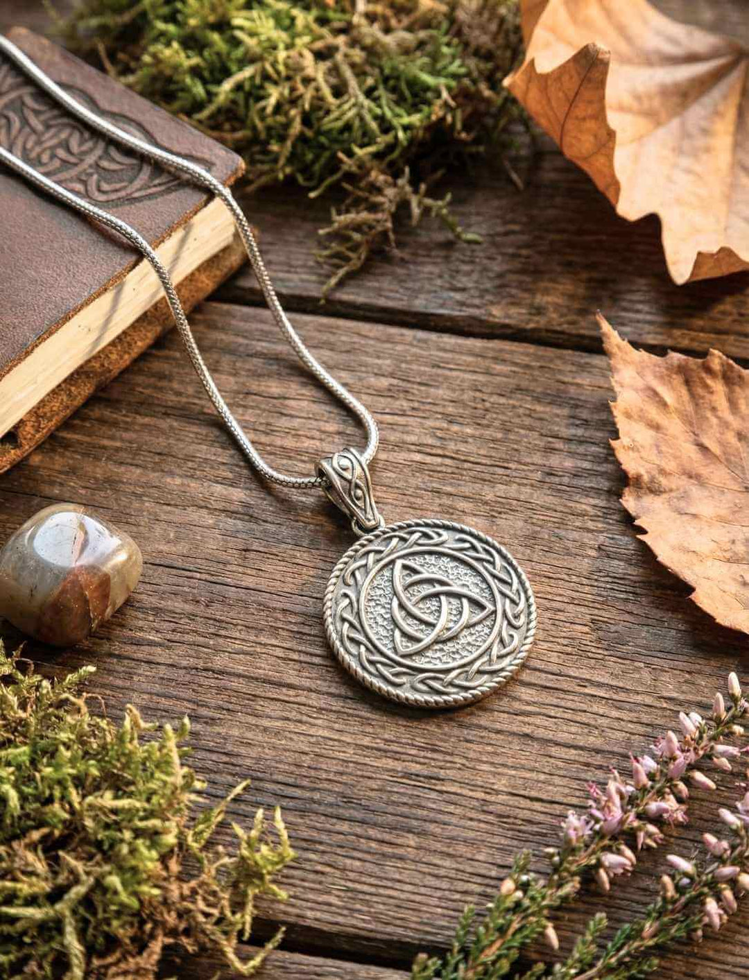 Runder keltischer Triquetra Anhänger aus Edelstahl, Detailaufnahme auf Holzuntergrund