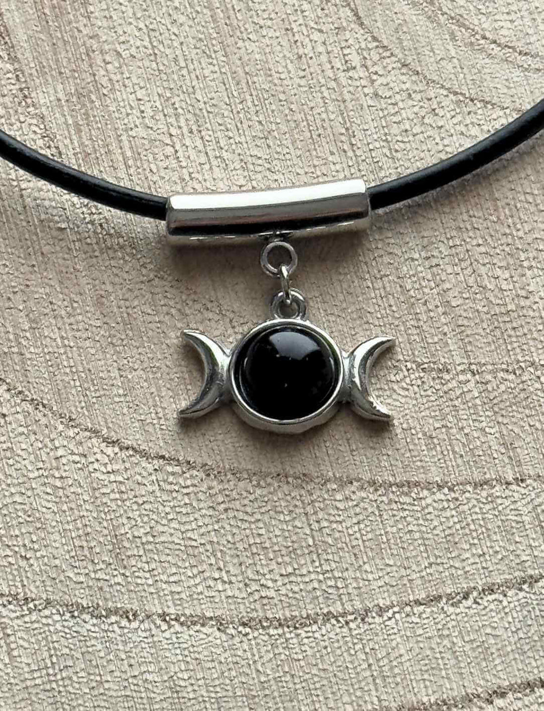 Mystischer Dreimondzirkel Anhänger mit schwarzem Onyx und Edelstahl auf runder Holzfläche