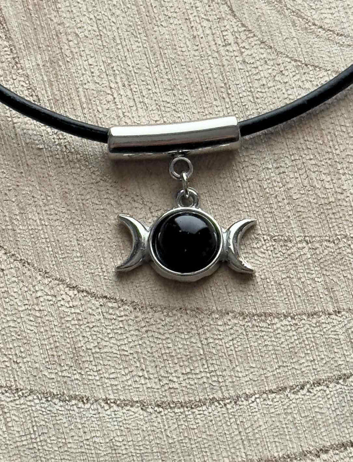 Mystischer Dreimondzirkel Anhänger mit schwarzem Onyx und Edelstahl auf runder Holzfläche