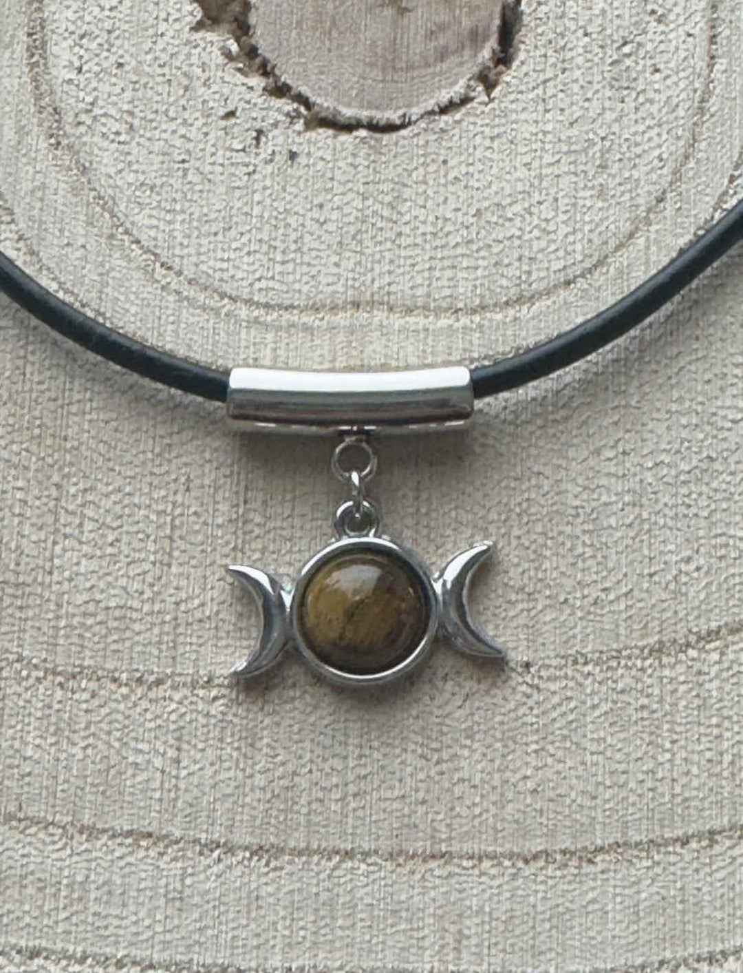 Edelstahl-Dreifachmond-Anhänger mit goldbraunem Tigerauge, präsentiert auf hellem Holz