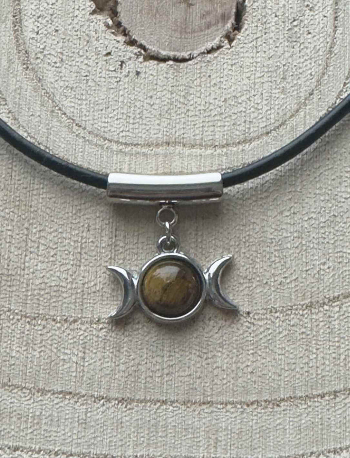 Edelstahl-Dreifachmond-Anhänger mit goldbraunem Tigerauge, präsentiert auf hellem Holz