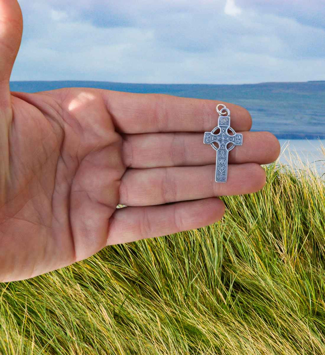 Erin's Erbe keltisches Silberkreuz wird in der Hand gehalten.