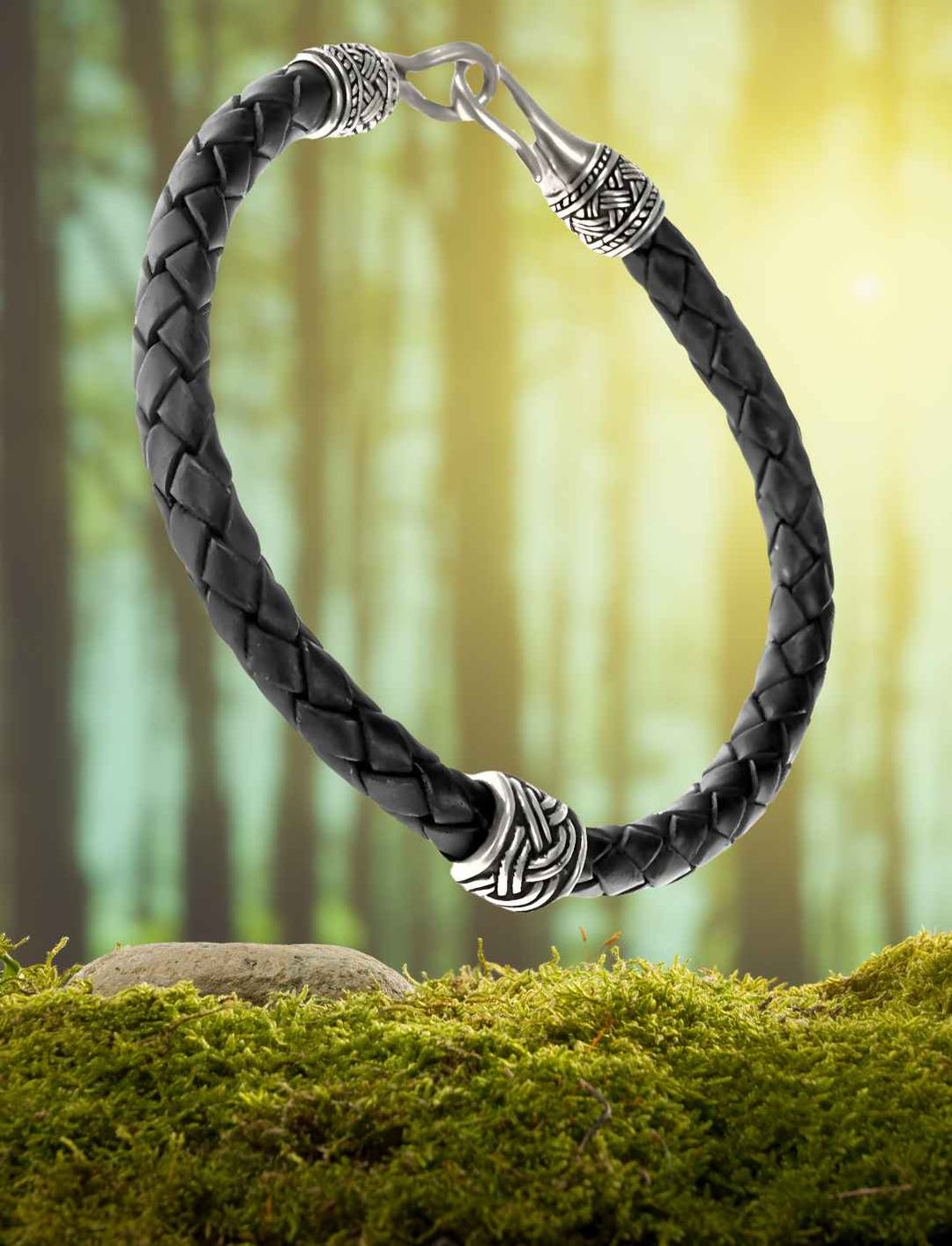 Geflochtenes Lederarmband mit versilberten Bronze Elementen. Inspiriert von der nordischen Wikinger-Kultur, auf Moos/Wald Hintergrund.