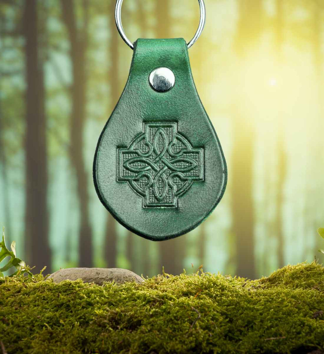Rindleder 'Gaelic Cross' Schlüsselanhänger vor einem moosbedeckten Waldhintergrund – Spüre die Verbindung zur gälischen Natur mit Runental.de
