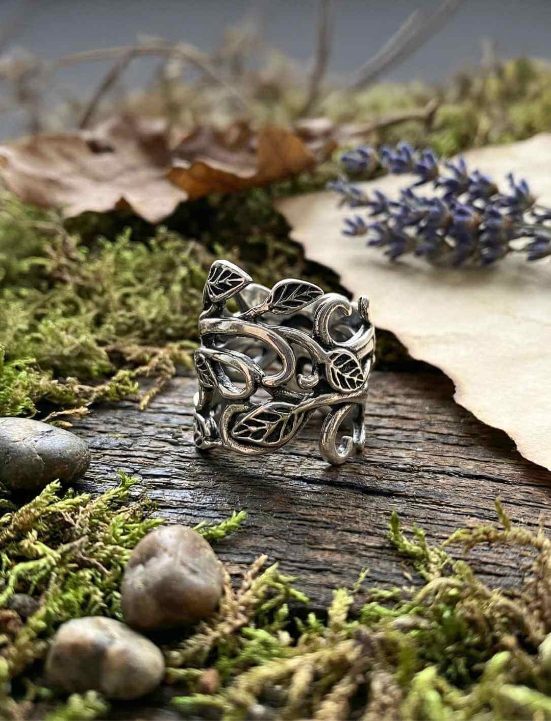 Breiter Silberring mit verwobenen Blättern in natürlicher Waldkulisse