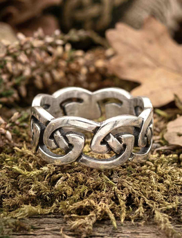Keltischer Knoten Ring aus Silber auf Moos und Holz, Symbol für ewige Pfade und Verbundenheit