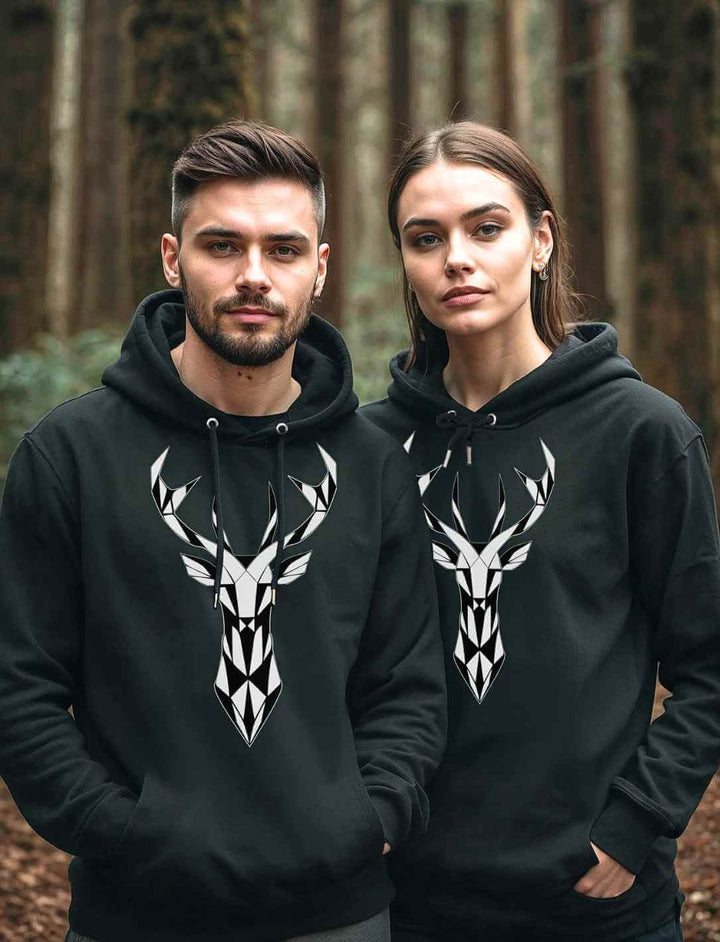 Junges Paar mit „Geometric Deer“-Hoodies im Wald – Ein Paar trägt die schwarzen Hoodies mit geometrischem Hirsch-Design, umgeben von einem mystischen Wald.