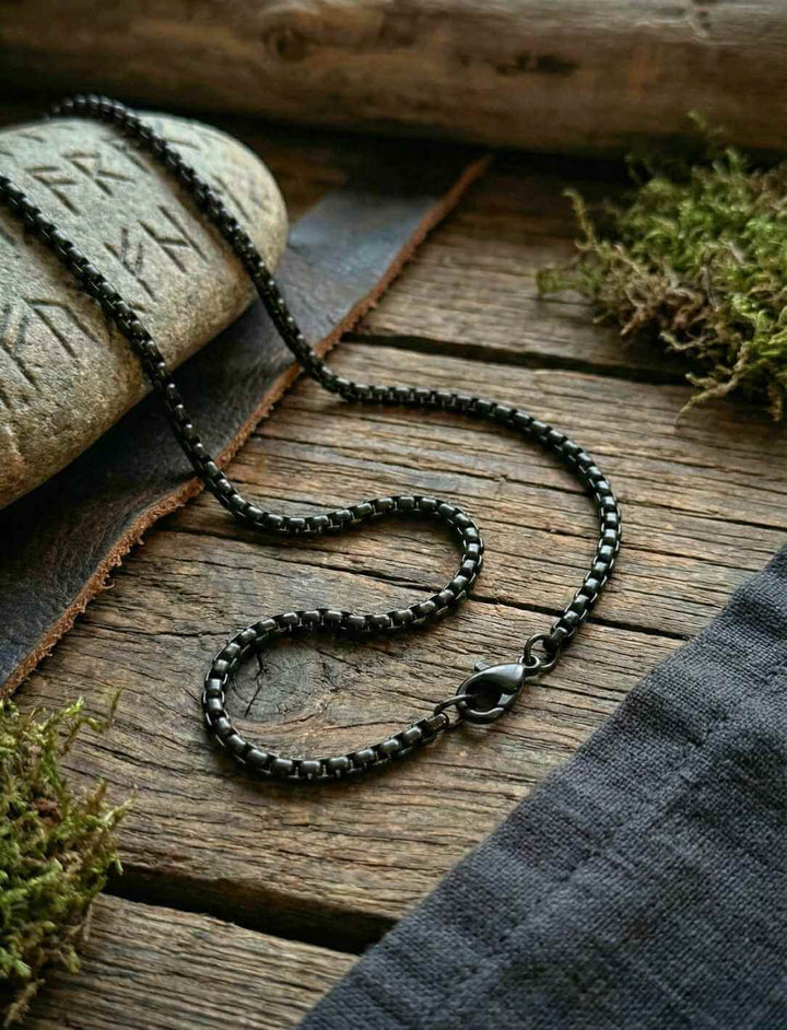 Schwarze Gliederkette aus titanbeschichtetem Edelstahl auf Holz mit Runenstein