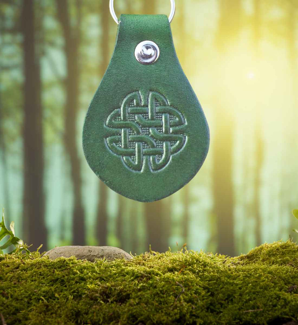 Der 'Hibernias Knoten' Leder-Schlüsselanhänger vor einem lebendigen Wald- und Mooshintergrund, eingetaucht in das Erbe Irlands, angeboten von Runental.de.