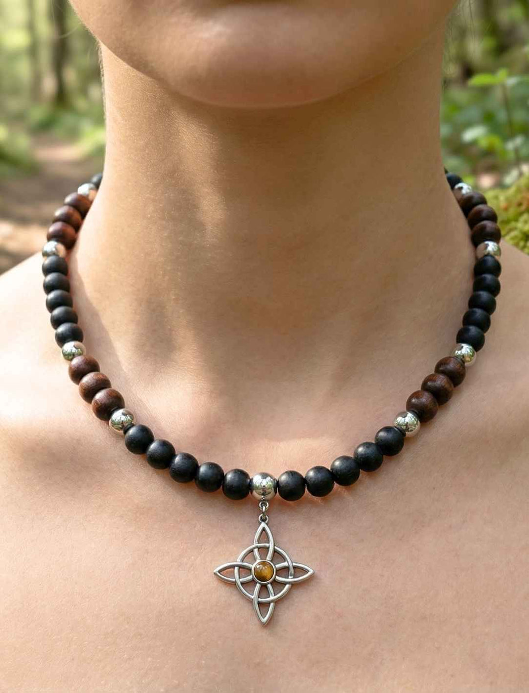 Keltische Holzperlenkette mit vierarmigem Knotenanhänger mit Tigerauge an einer Frau im Wald