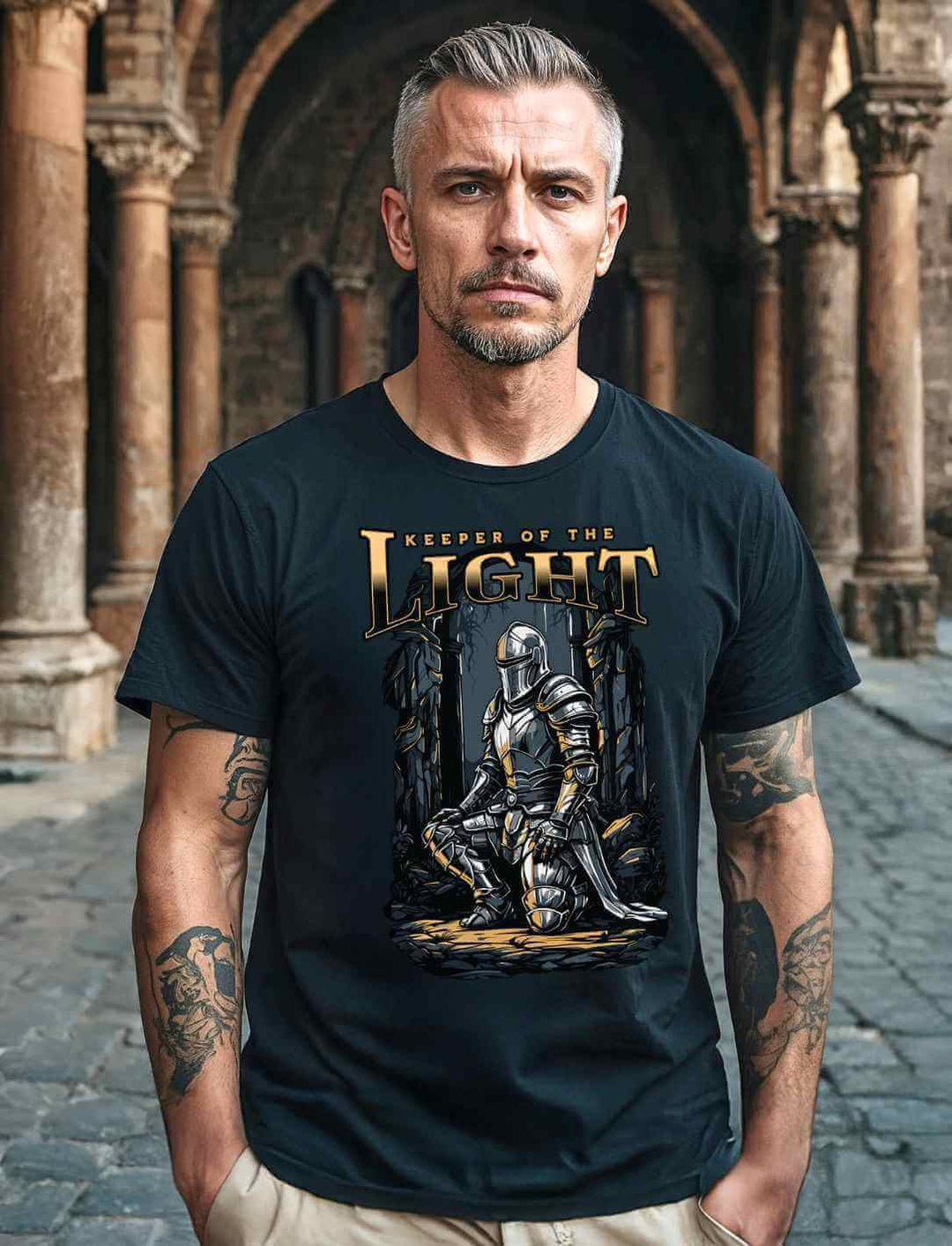 Mann vor einer mittelalterlichen Kirche, trägt das schwarze Organic Shirt Keeper of the Light mit Paladin Motiv.