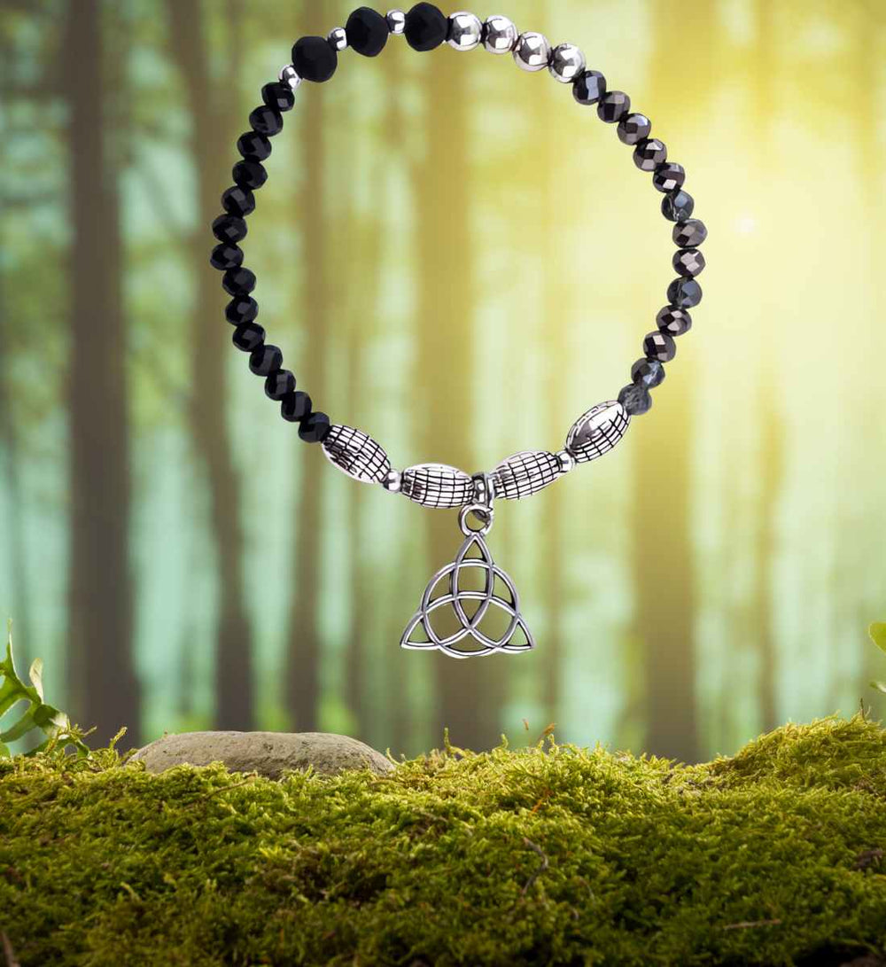 Armband des ewigen Knotens, präsentiert in seiner natürlichen Pracht auf einem Moos- und Waldhintergrund, symbolisiert die tiefe Verbindung zur Erde.