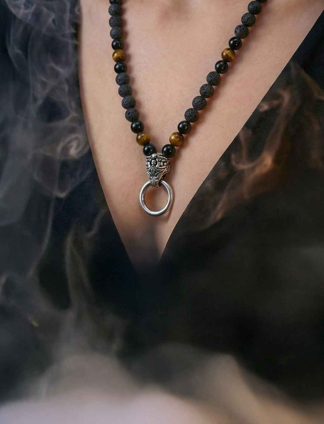 Getragene Natursteinkette aus Lava, Obsidian und Tigerauge mit Clipring in einer rauchigen Szene